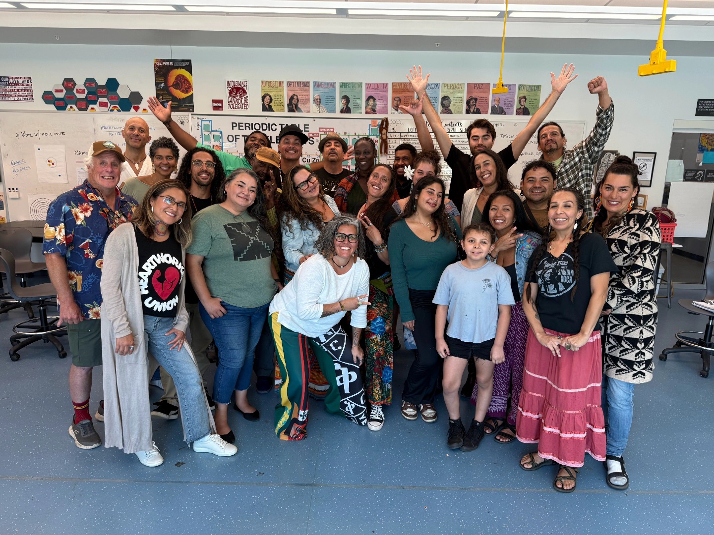 Community members gathered together, smiling and raising their hands in celebration.